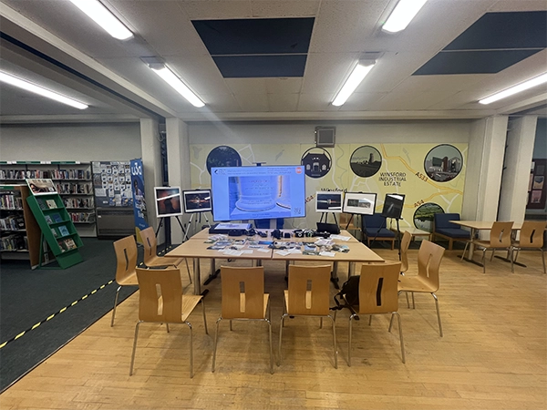 Overhead view of a community photography workshop table featuring cameras, prints, and still-life composition tools